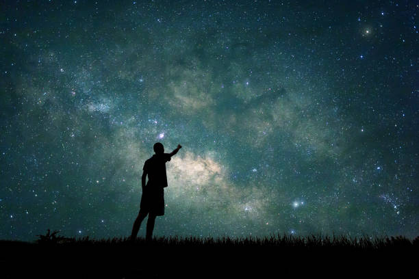 Silhouette of a person pointing at the starry night sky